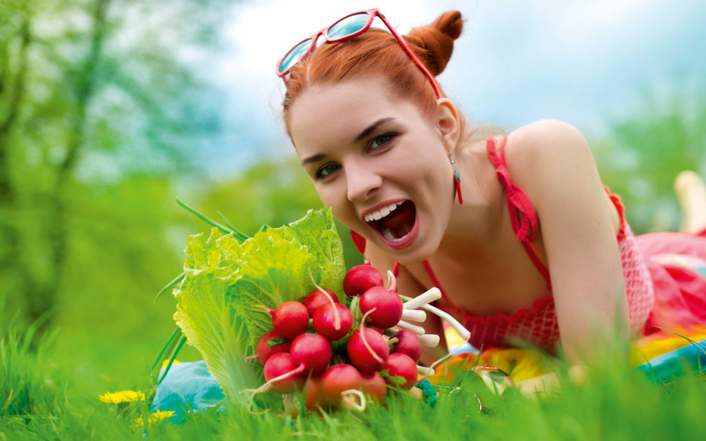 Jeune femme dévorant des radis sur l'herbe